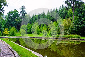 Photo of stone road near the lake in green park at summer