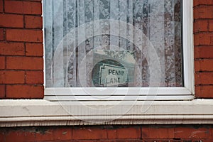 Photo of the street sign of Penny Lane in a window of a house in Penny Lane street. Liverpool, England.