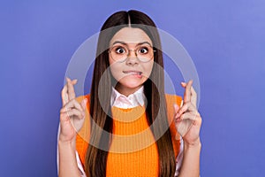 Photo of stressed nervous schoolgirl dressed orange vest in glasses hold fingers folded biting lip isolated on purple