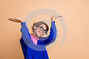 Photo of struggling hardworking girl look up arms palms hold heavy empty space isolated on beige color background