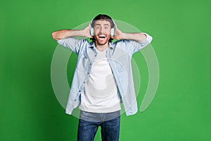 Photo of stubbled guy open mouth excited smiling wear headphones denim shirt jeans isolated green color background photo