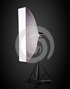 Photo studio lighting stands with flash and softbox isolated on the black.