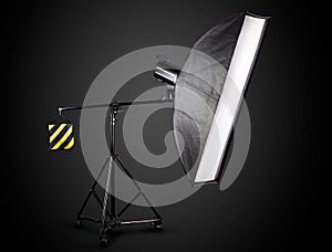 Photo studio lighting stands with flash and softbox isolated on the black