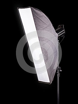 Photo studio lighting stands with flash and softbox isolated on the black.