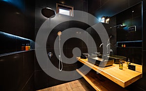 Photo of stylish dark bathroom interior with big shower. Modern minimalism style bathroom interior in black tones and