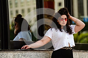 Photo of stylish young girl in fashionable sunglasses and clothes posing on the city street