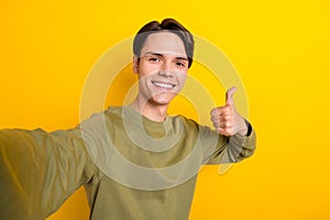 Photo of successful glad man blogger wear khaki clothes arm thumb up recommend modern device shop isolated on yellow