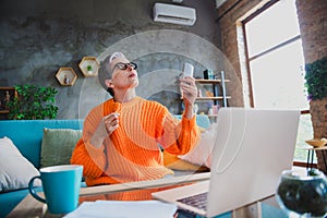 Photo of suffering heat elderly lady wear orange pullover turning on broken air conditioning indoors apartment room