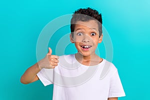 Photo of surprised amazed boy wear trendy white clothes thumb up wow cool special offer shop sale isolated on cyan color