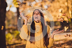 Photo of surprised girl enjoy throw catch air fly fall maple leaves in town center park woods outside wear knitted