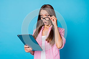 Photo of surprised lady hold tablet look screen open mouth wear specs pink striped shirt isolated blue background