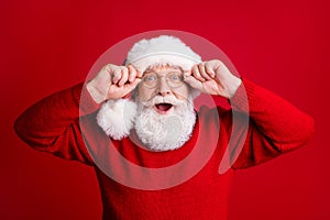 Photo of surprised shocked old man in santa claus hat enjoy rejoice winter newyear noel discounts touch glass wear shine