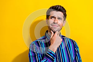 Photo of suspicious gloomy man dressed striped shirt hold finger on chin look empty space isolated on vivid yellow color