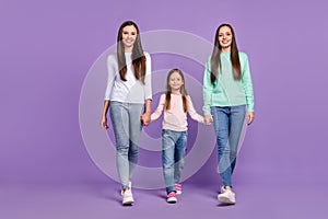 Photo of sweet adorable daughters mom dressed casual sweaters walking holding hands smiling isolated purple color