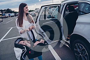 Photo of sweet cheerful mom small daughter wear casual outfits open door putting car seat inside automobile vehicle