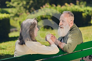 Photo of sweet cheerful senior couple wear casual clothes walking having rest sitting bench holding arms smiling outside