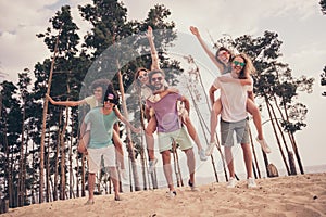 Photo of sweet friendly six young buddies dressed casual outfits walking holding arms piggyback outdoors countryside