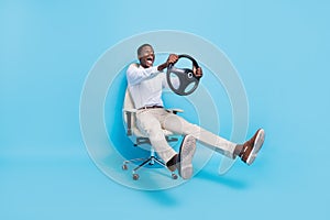 Photo of sweet funky dark skin man wear white shirt smiling sitting chair holding steering wheel isolated blue color