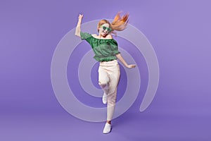 Photo of sweet funky young lady wear green blouse dark glasses smiling dancing isolated purple color background