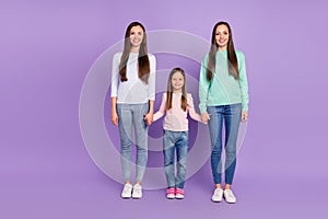 Photo of sweet funny mommy two daughters wear casual pullovers holding hands walking smiling isolated violet color