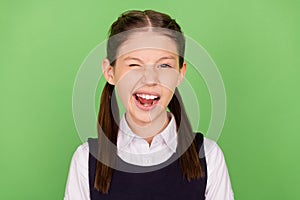 Photo of sweet funny school girl dressed formal clothes winking smiling  green color background