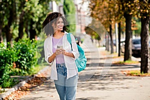 Photo of sweet good mood lady wear white shirt rucksack enjoying journey texting modern gadget outside urban city park