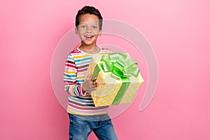 Photo of sweet nice positive schoolboy curly hairstyle dressed striped long sleeve hold present box isolated on pink