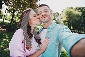 Photo of sweet pretty husband wife dressed casual clothes kissing recording self video enjoying sunshine outside