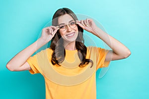 Photo of sweet shiny girl dressed yellow t-shirt arms eyewear smiling empty space  teal color background