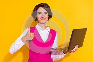 Photo of sweet shiny young lady wear pink suit holding modern device showing thumb up smiling isolated yellow color