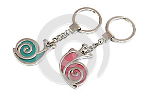 A pair of green and red snails keychains against a white backdrop photo