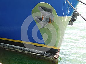 The retracted anchor at the hull of a boat ship vessel docked at sea