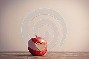 Photo of tasty red apple and heart shaped chocolate candy on the