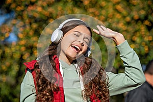 photo of teen girl singing and listening music. teen girl listening music outdoor.