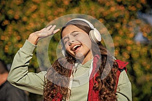 photo of teen girl singing and listening music. teen girl listening music outdoor.