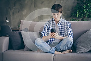 Photo of teenager school boy enjoy sit comfy couch staying home quarantine time hold telephone hands read teacher