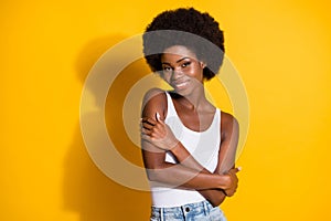 Photo of tender black young girl embrace herself wear white tank-top isolated yellow color background