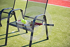 Photo of tennis racket and ball on chair at court