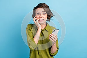 Photo of terrified charming lady short hairstyle hands hold telephone gnaw bite nails frightened stressed look camera