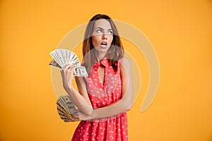 Photo of thinking young brunette woman in red dress hilding two