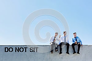 Photo of thoughtful businessmen sitting and relaxing on rooftop during break in office