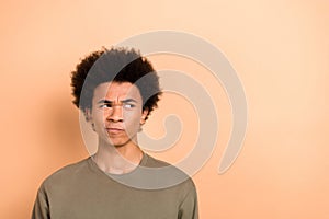 Photo of thoughtful uncertain doubtful guy with afro hairstyle dressed khaki shirt look empty space isolated on beige