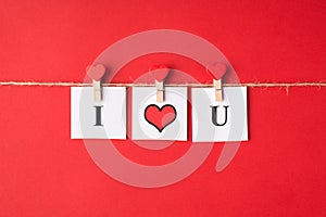 Photo of three paper cards with words i love you hanging with pins on rope string isolated bright color red backdrop