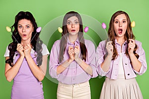 Photo of three young girls amazed shocked surprised news hold eggs sticks easter holiday isolated over green color