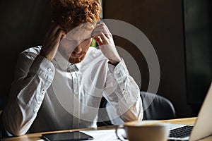 Photo of tired readhead businessman, touching his head, looking