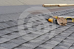 Asphalt tile roof and tool belt lying on new house under construction photo