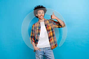 Photo of toothy beaming guy with perming coiffure wear plaid jacket showing thumb up hand in pocket isolated on blue