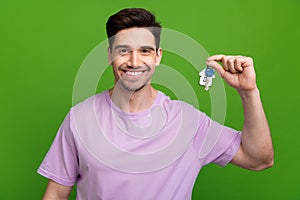 Photo of toothy beaming man with brunet hair dressed purple t-shirt holding keys from new apartments isolated on green