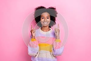 Photo of toothy beaming positive girl with perming coiffure wear knit sweater directing empty space isolated on pink
