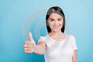 Photo of toothy cheerful kind cute nice girl thumbing you up giving you perfect feedback while isolated blue background